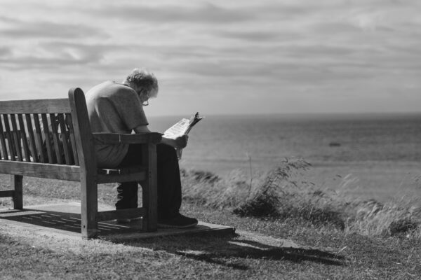 Photo by Craig Dennis: https://www.pexels.com/photo/grayscale-photo-of-man-sitting-on-brown-wooden-bench-reading-news-paper-during-day-time-128428/